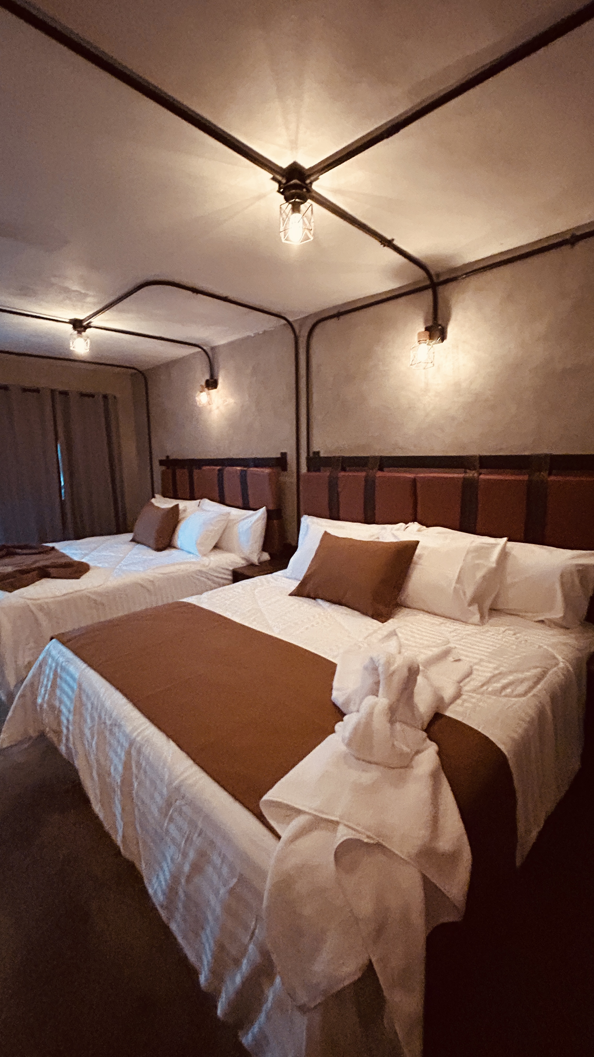 Camas queen con blancos premium y pie de cama color cognac en habitación doble del Hotel Van Gogh